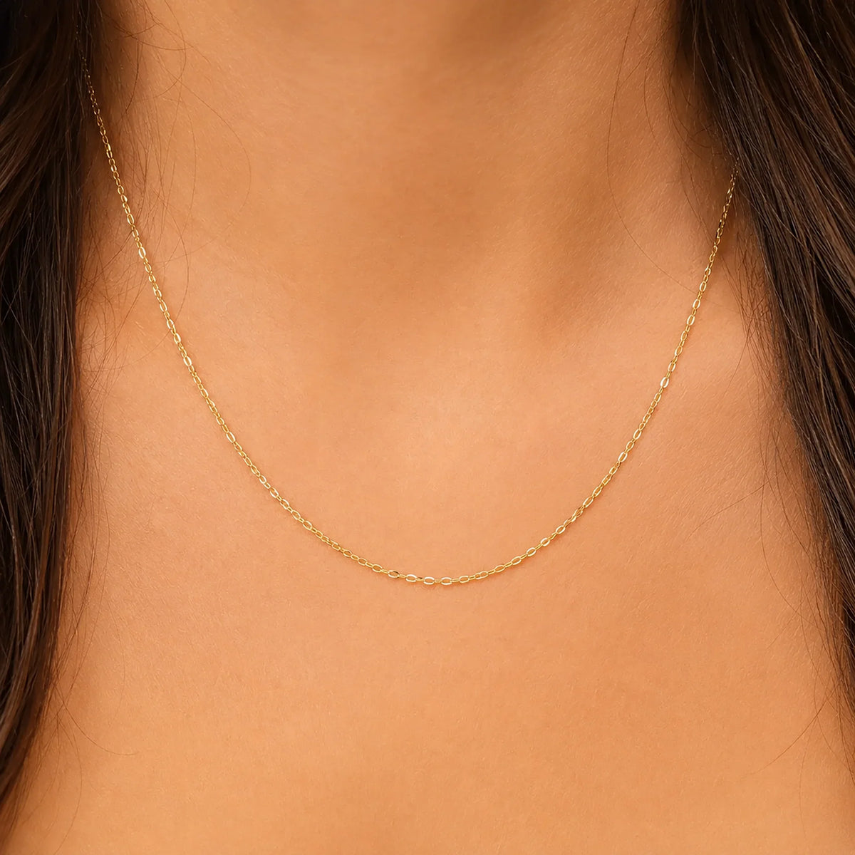 Close-up of a person wearing a solid 14K gold anchor chain necklace by Lucche.