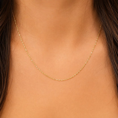 Close-up of a person wearing a solid 14K gold anchor chain necklace by Lucche.