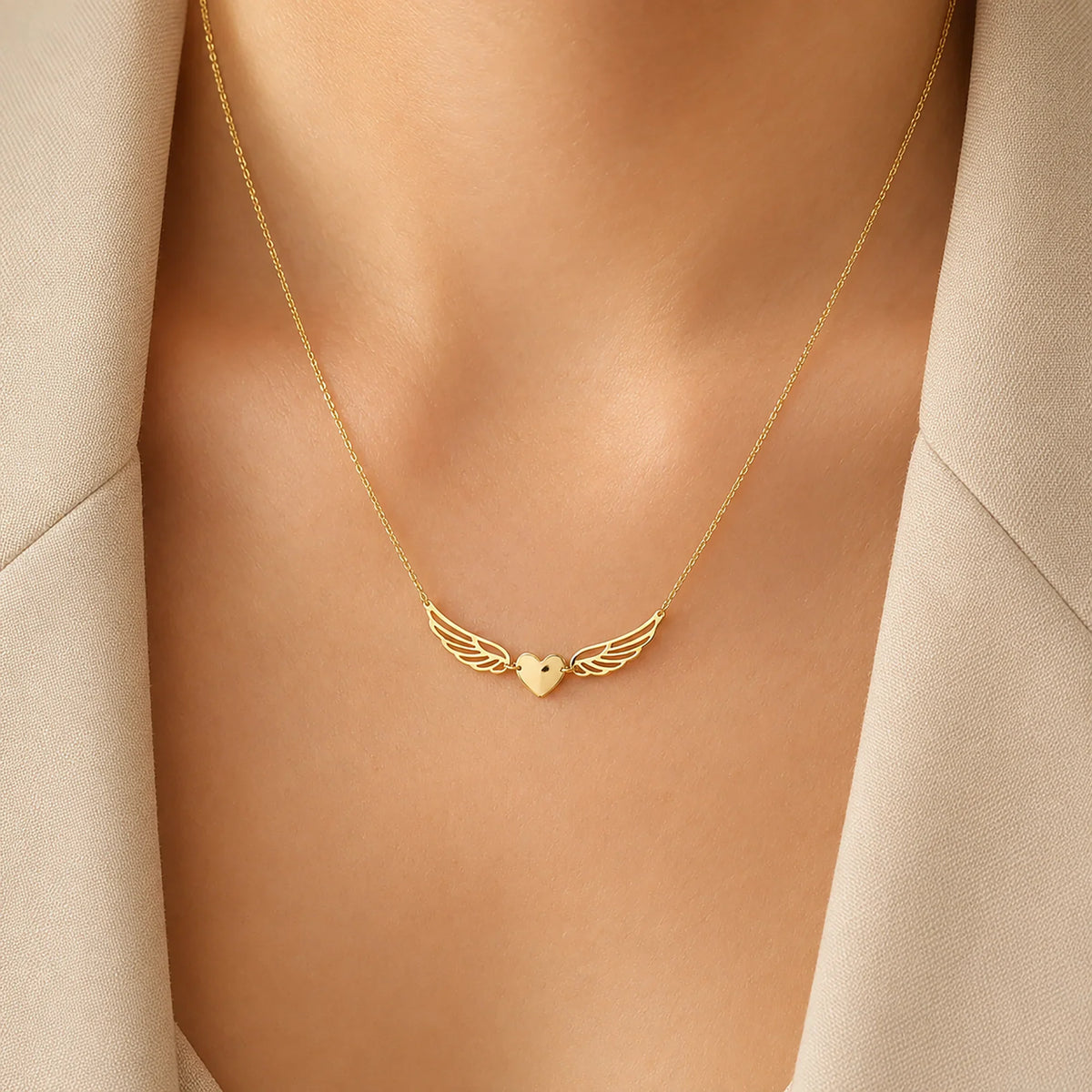 Lucche 14K gold necklace featuring a heart pendant with angel wings on a woman's neck